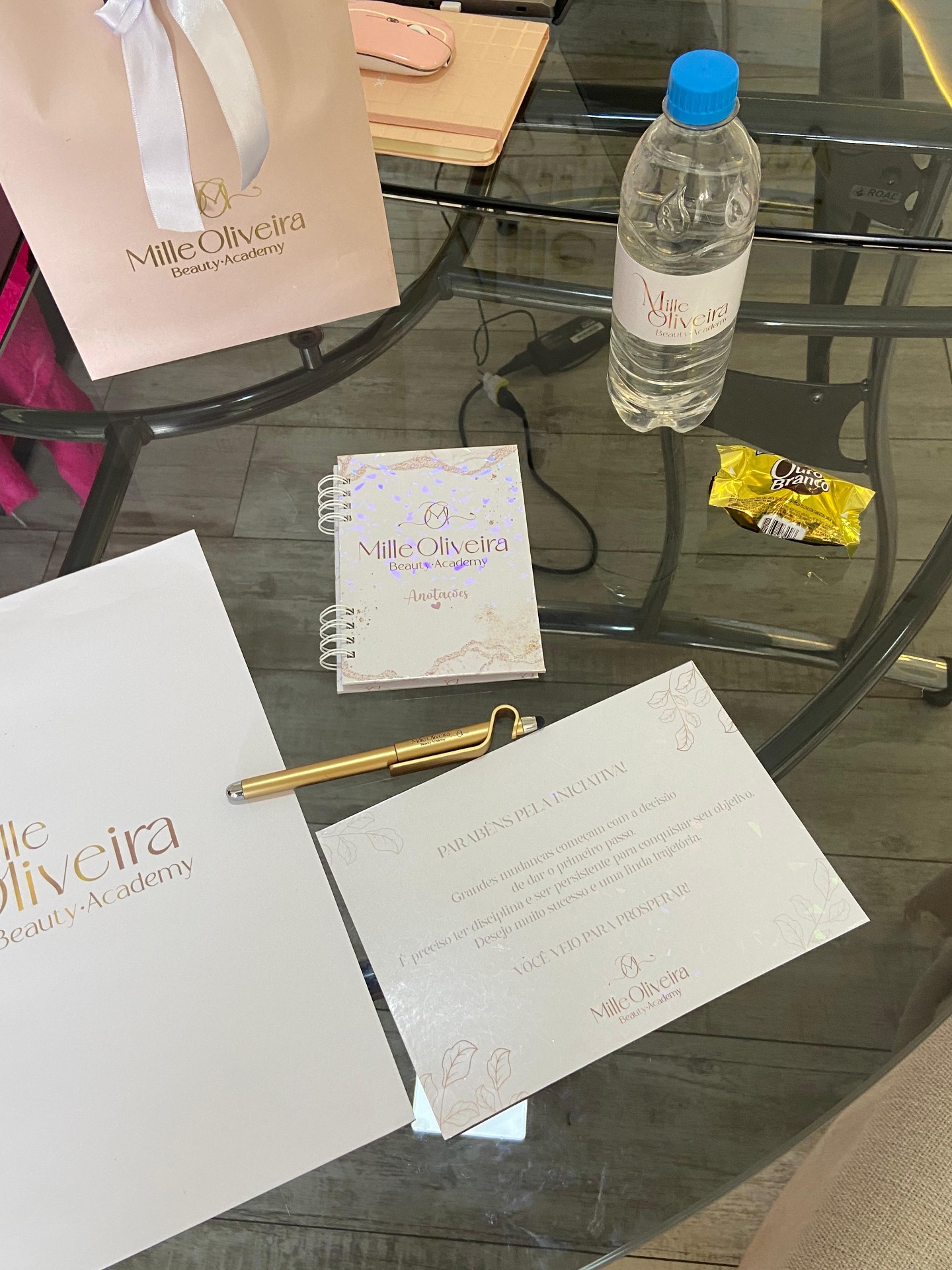 Kit de boas-vindas da Mille Oliveira: sacola personalizada, apostila, caderno de anotações, caneta dourada, garrafinha e cartão